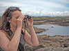A Woman Using Kowa Genesis 22 10x22mm Prominar XD Binocular Outdoors