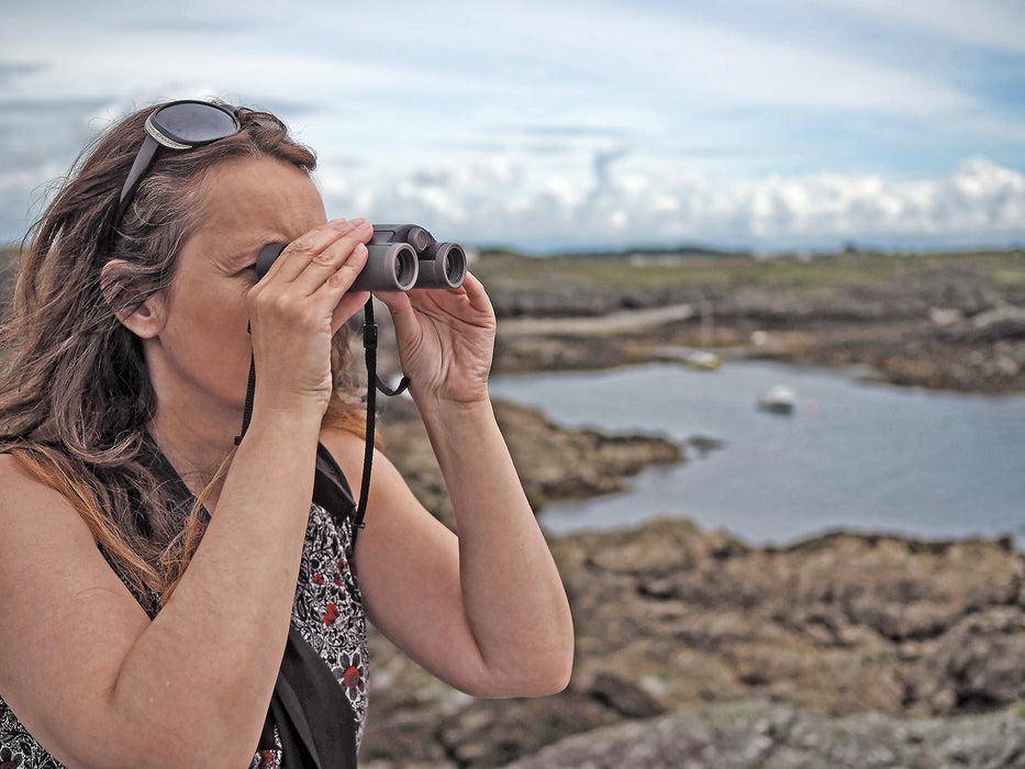 A Woman Using Kowa Genesis 22 10x22mm Prominar XD Binocular Outdoors